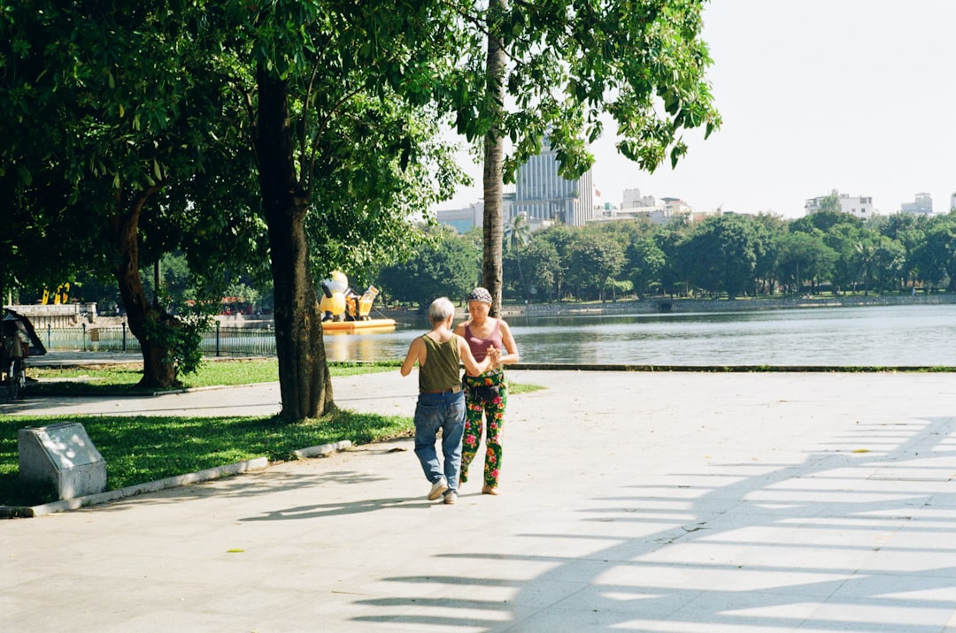 Two people walking by a lake in a park.