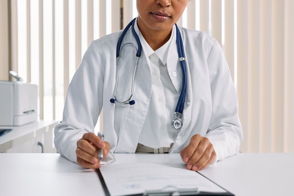 A focused doctor with stethoscope recording patient details in an office setting.