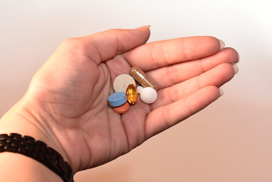 A close-up image of a human hand holding assorted pills, showcasing diverse colors and shapes.