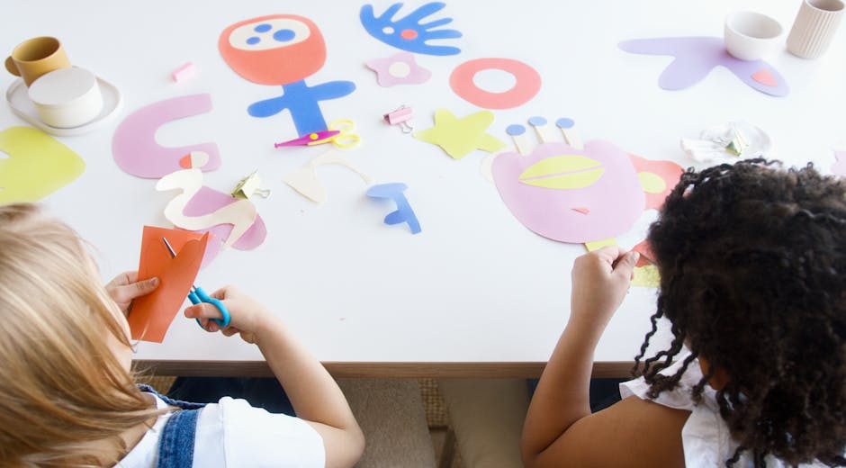 Two children enjoying an art class with colorful paper cutouts, fostering creativity and fun.
