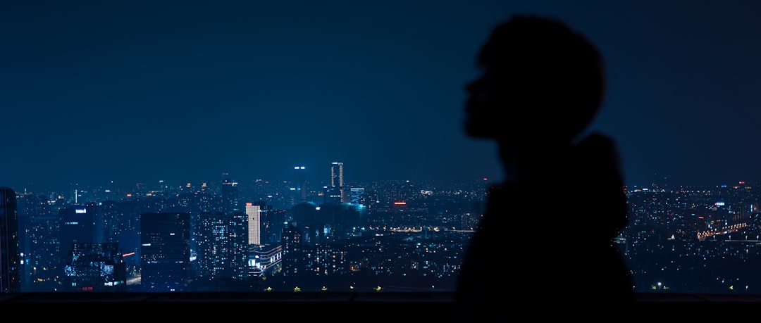 a man standing in front of a window overlooking a city at night