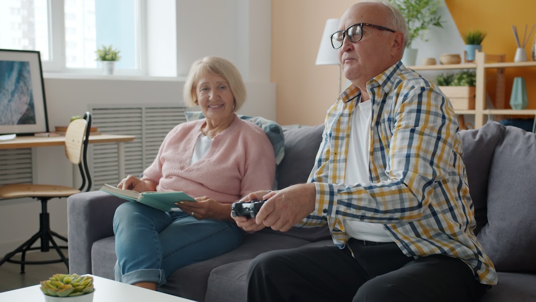 Elderly couple playing video games on the couch.