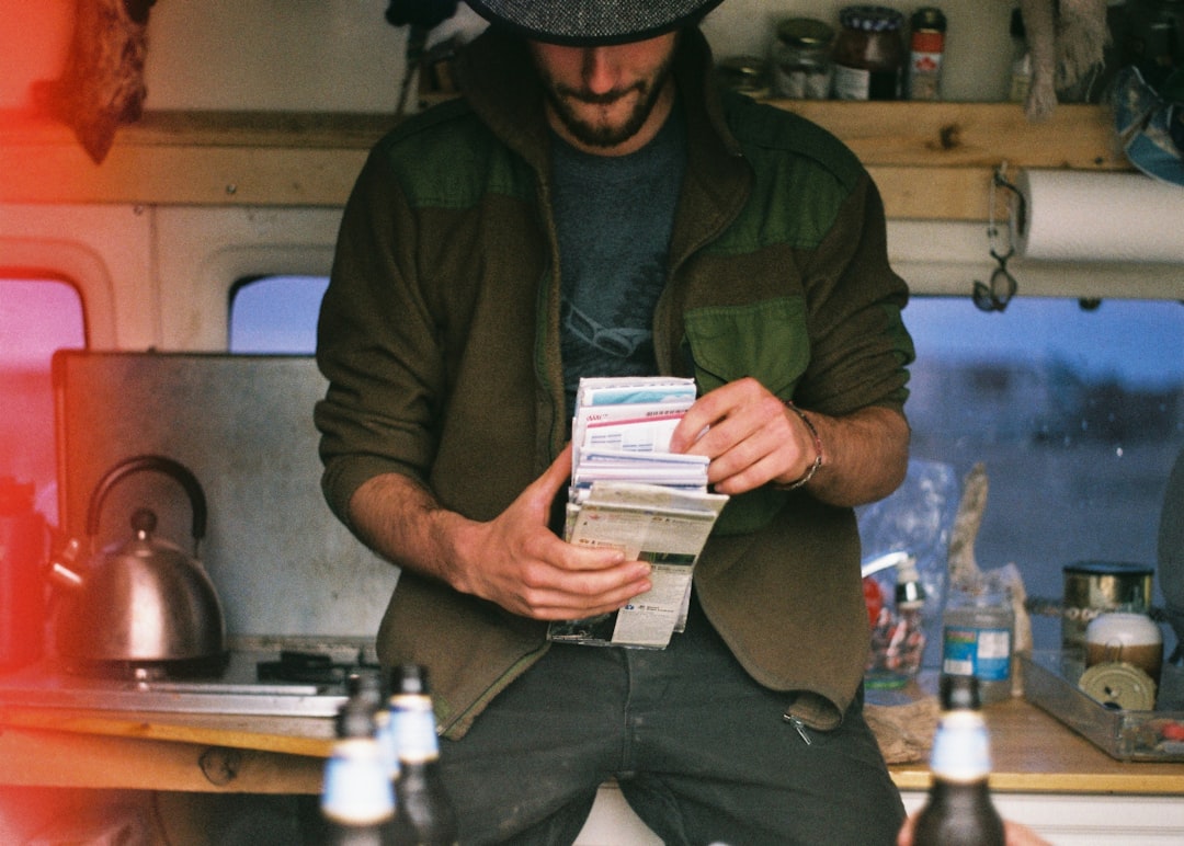 man in brown and green jacket holding paper liftlets