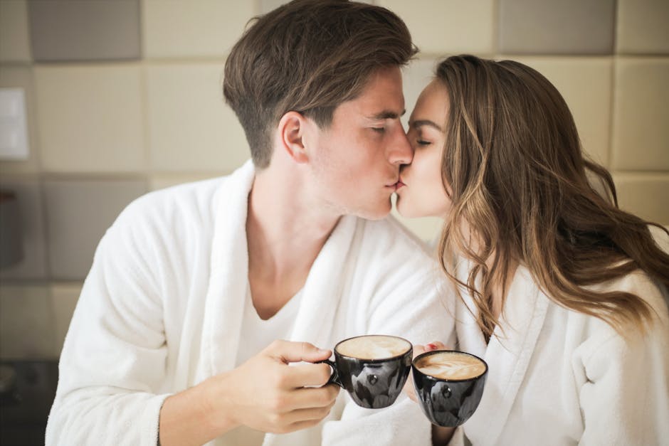 Couple in bathrobes sharing an intimate moment with coffee indoors.