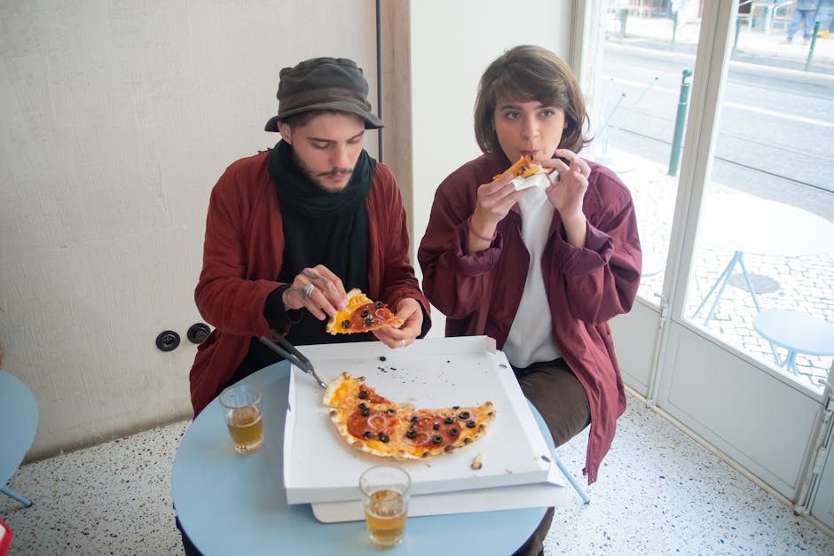 Young couple enjoys pizza at a cozy café in Portugal, capturing a relaxed urban dining vibe.